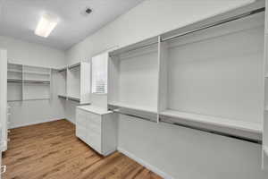 Walk in closet with light wood finished floors