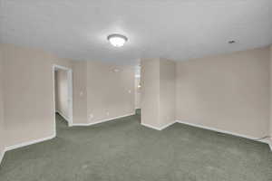 Unfurnished room with dark colored carpet and a textured ceiling