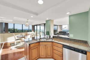 Kitchen featuring stainless steel dishwasher, recessed lighting, plenty of natural light, dark stone countertops, and hanging light fixtures