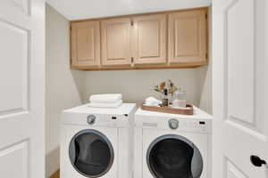 Laundry area featuring washing machine and dryer and cabinet space