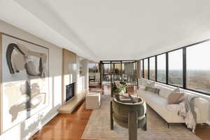 Living area with wood finished floors, a glass covered fireplace, and heating unit