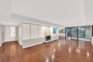 Unfurnished living room with wood finished floors, a glass covered fireplace, and recessed lighting