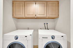 Laundry room featuring independent washer and dryer and cabinet space