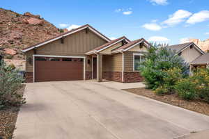 Craftsman inspired home featuring an attached garage, stone siding, concrete driveway, and board and batten siding