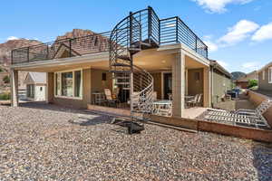 Rear view of property featuring a patio, stairs, and stucco siding