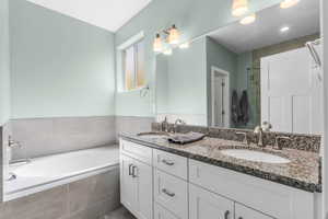 Full bath featuring double vanity, a bath, and a stall shower