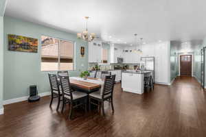 Dining space with a chandelier, dark wood finished floors, and recessed lighting
