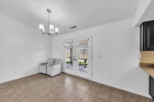 Unfurnished dining area with french doors, a chandelier, and light tile patterned flooring