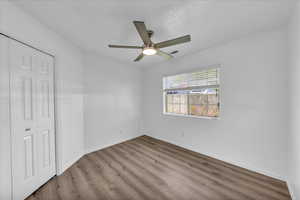 Unfurnished bedroom with wood finished floors, a closet, and a ceiling fan