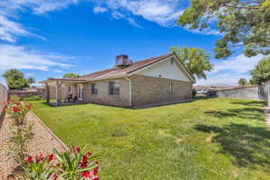 Rear view of property with brick siding, a fenced backyard, a patio, and a chimney