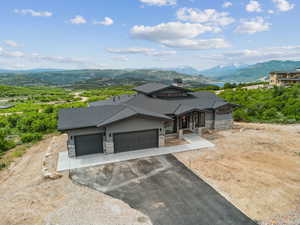View of front of property with stone siding, a mountain view, an attached garage, and driveway