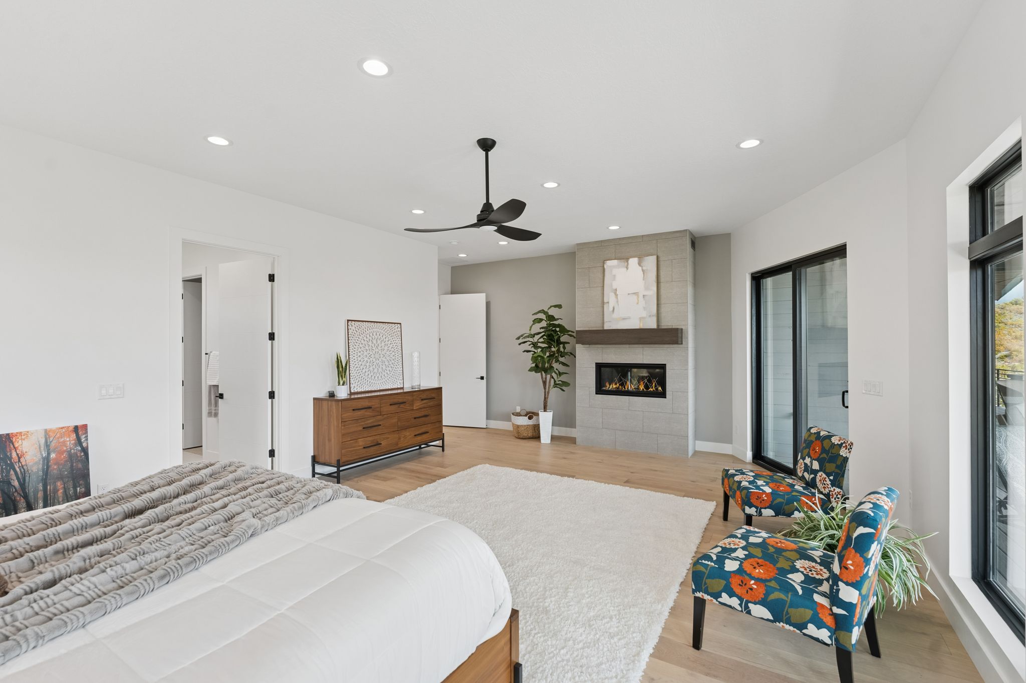 Bedroom featuring light wood-style flooring, recessed lighting, a tiled fireplace, and ceiling fan