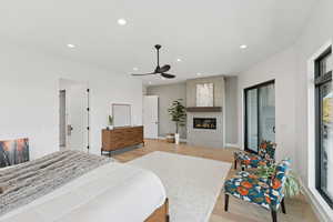 Bedroom featuring light wood-style flooring, recessed lighting, a tiled fireplace, and ceiling fan