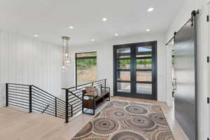 Entryway featuring a barn door, wood finished floors, french doors, and recessed lighting