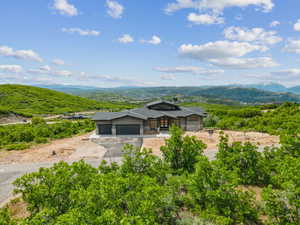 View of front of home with a garage, asphalt driveway, stone siding, and a mountain view