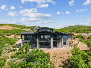 Back of property featuring a balcony, a patio, a mountain view, and stone siding