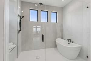 Bathroom featuring a stall shower, a freestanding tub, and tile walls
