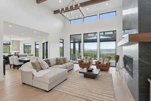 Living area with a towering ceiling, light wood finished floors, a fireplace, recessed lighting, and beam ceiling