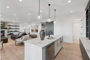 Kitchen with appliances with stainless steel finishes, light wood finished floors, recessed lighting, a center island with sink, and pendant lighting