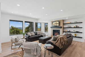 Living area with recessed lighting, a glass covered fireplace, light wood-style flooring, and a textured ceiling
