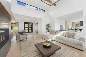 Living room with a glass covered fireplace, light wood-style flooring, a high ceiling, and recessed lighting