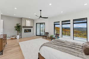 Bedroom with recessed lighting, light wood-style flooring, a fireplace, a mountain view, and access to exterior