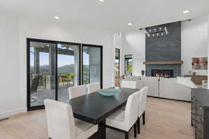 Dining area with light wood finished floors, recessed lighting, a chandelier, a high end fireplace, and a mountain view