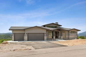 View of front of property with a garage, a mountain view, driveway, stone siding, and a shingled roof