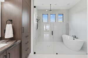 Full bathroom featuring a shower stall, a soaking tub, vanity, tile walls, and light tile patterned flooring