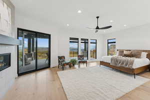 Bedroom featuring recessed lighting, light wood-style floors, access to outside, a fireplace, and ceiling fan