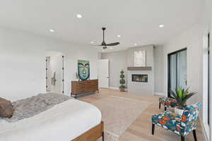 Bedroom with light wood finished floors, recessed lighting, a fireplace, and ceiling fan