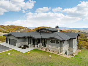 View of front of house with stone siding, a chimney, driveway, and a garage