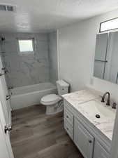 Bathroom with vanity, a textured ceiling, shower / tub combination, and wood finished floors