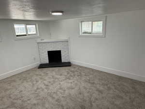 Unfurnished living room with a textured ceiling, a brick fireplace, and carpet