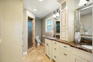 Full bathroom with double vanity, a shower stall, and recessed lighting