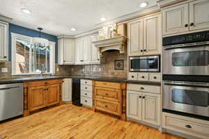 Kitchen with appliances with stainless steel finishes, light wood-type flooring, backsplash, recessed lighting, and hanging light fixtures