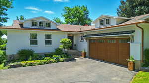 View of front of property with brick siding, driveway, an attached garage, and a shingled roof