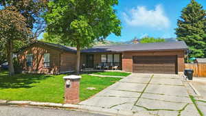 Ranch-style house with concrete driveway, brick siding, an attached garage, and a chimney