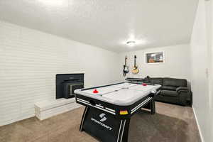 Rec room featuring carpet, a textured ceiling, and a wood stove