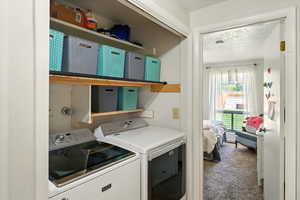 Laundry area with separate washer and dryer, carpet floors, and a textured ceiling
