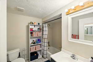 Full bath featuring shower / tub combo, vanity, tile patterned flooring, and a textured ceiling