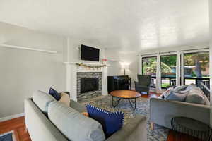 Living room featuring wood finished floors, a tile fireplace, and a textured ceiling