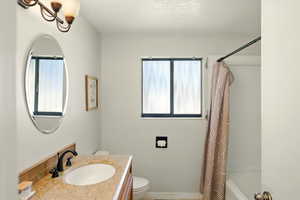 Bathroom featuring vanity, shower / bathtub combination with curtain, and a textured ceiling
