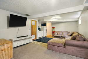 Carpeted living room with a textured ceiling