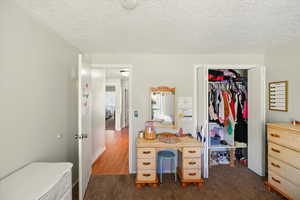 Bedroom featuring dark colored carpet, a textured ceiling, and a closet