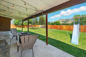 Fenced backyard featuring a patio, a mountain view, a trampoline, and a fire pit