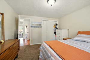 Bedroom featuring a closet, carpet floors, and a textured ceiling