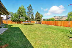 Fenced backyard featuring a mountain view and a trampoline