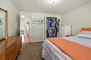 Carpeted bedroom with a closet and a textured ceiling