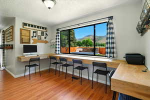 Home office with wood finished floors and a textured ceiling